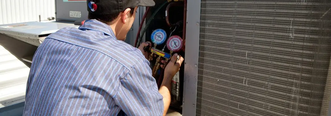HVAC technician servicing a condenser unit in Lakeland Village
